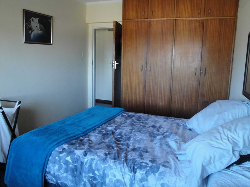 A bedroom featuring floor-to-ceiling built-in wooden cupboards, providing ample storage space within the room.