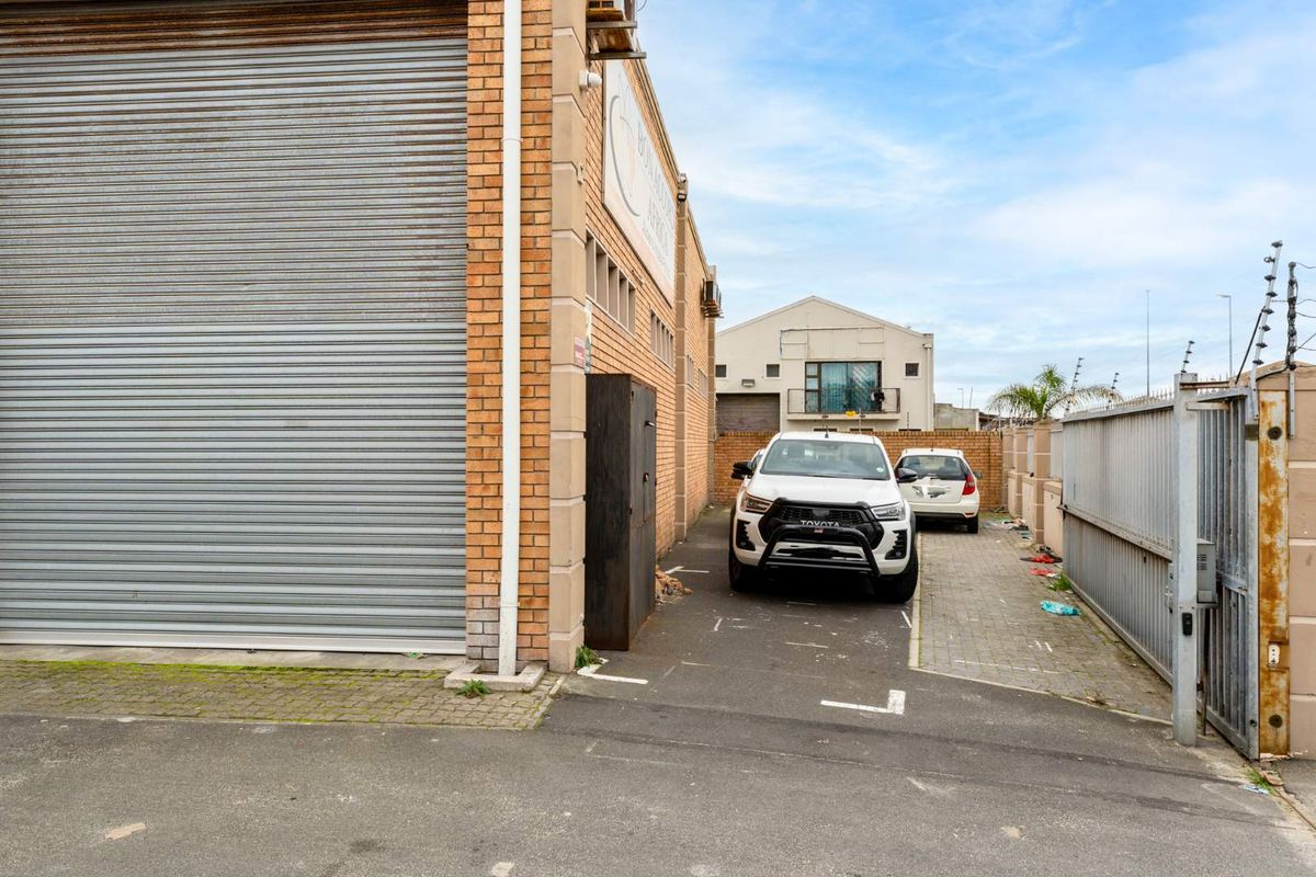 Rear exterior view of the office property featuring a large roller shutter door, paved driveway access, and secure perimeter fencing.