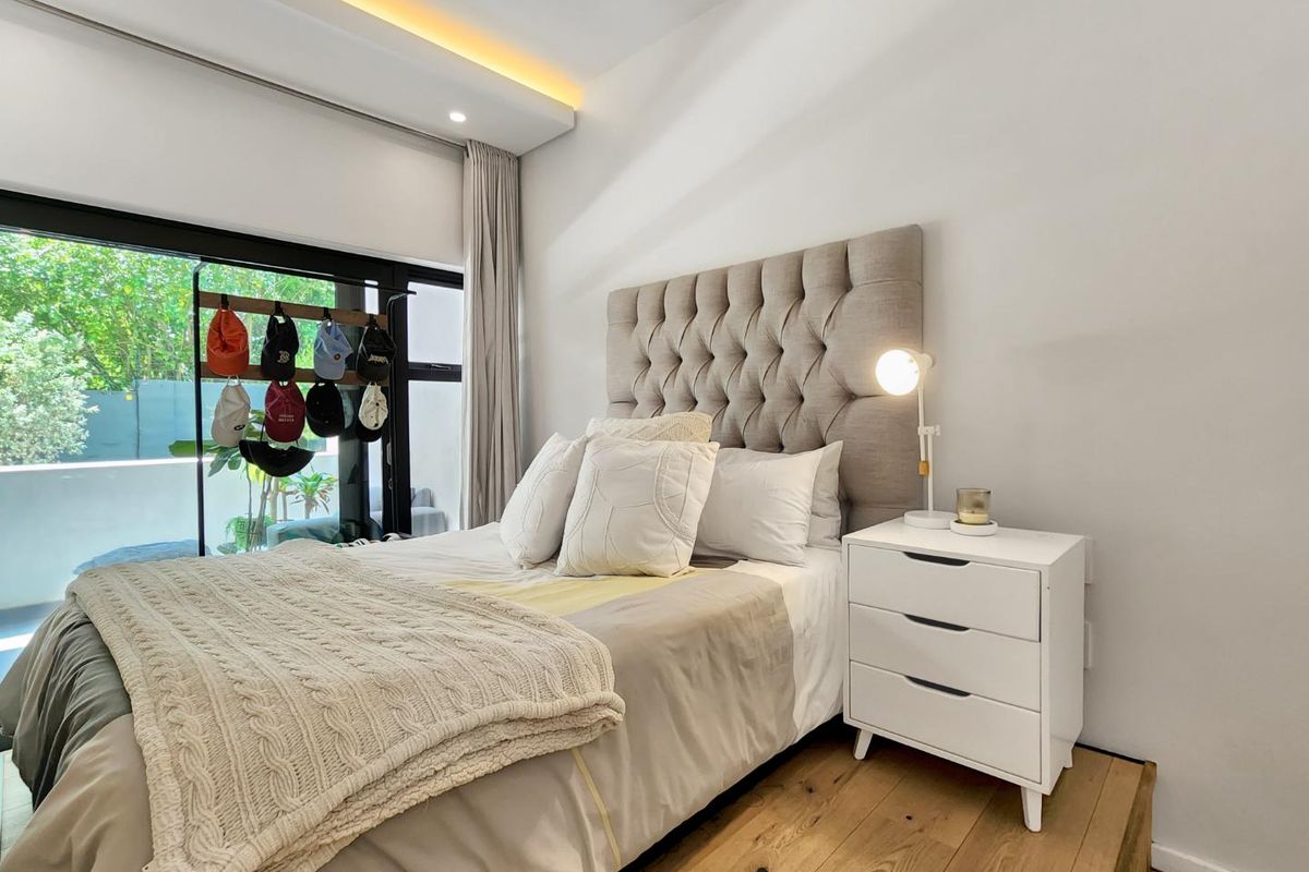 A well-maintained bedroom featuring a raised timber floor platform, recessed ceiling lighting, and large sliding glass doors providing access to an outdoor area.