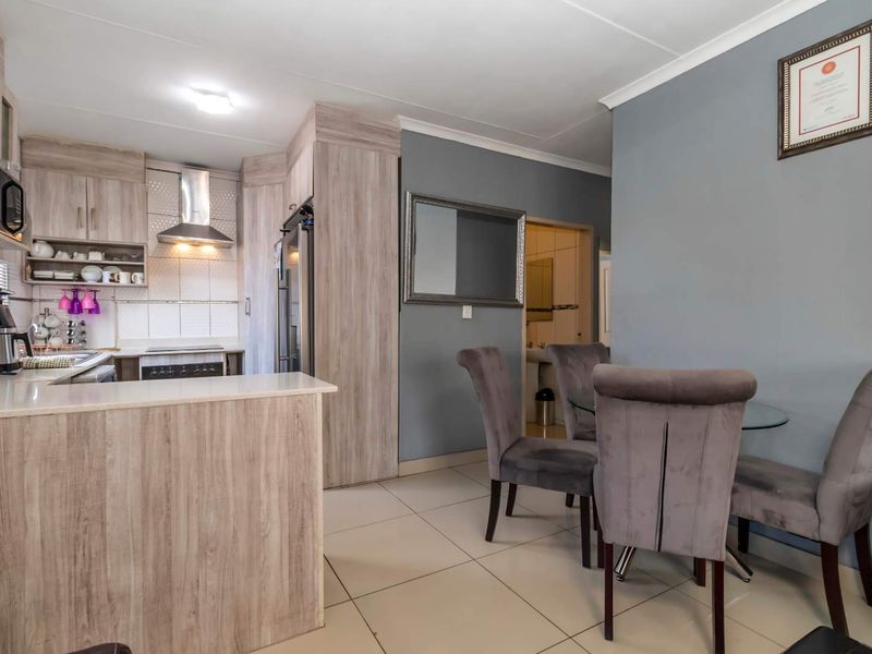 Open-plan kitchen and dining area featuring modern wood-look cabinetry, built-in appliances, and neutral tiled flooring.