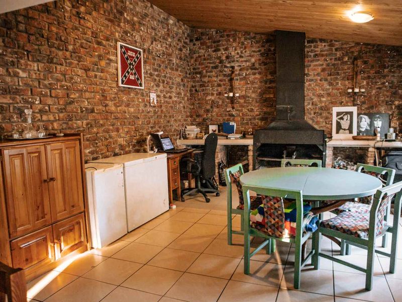 A rustic living area featuring an exposed brick wall, a built-in fireplace, tiled flooring, and a timber-clad ceiling.