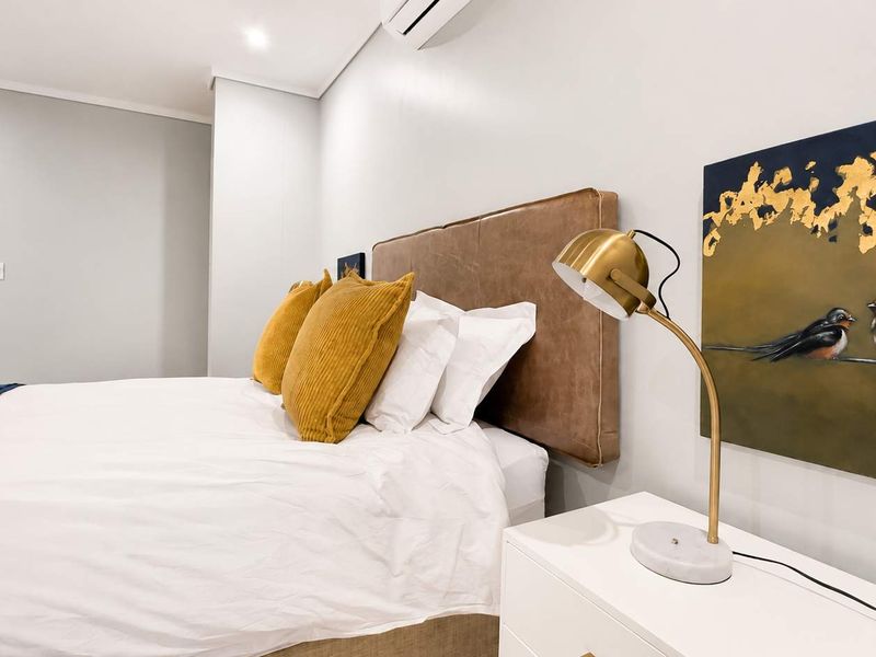 A well-maintained bedroom featuring neutral walls, recessed lighting, and an integrated air conditioning unit, with direct access to an en-suite bathroom.