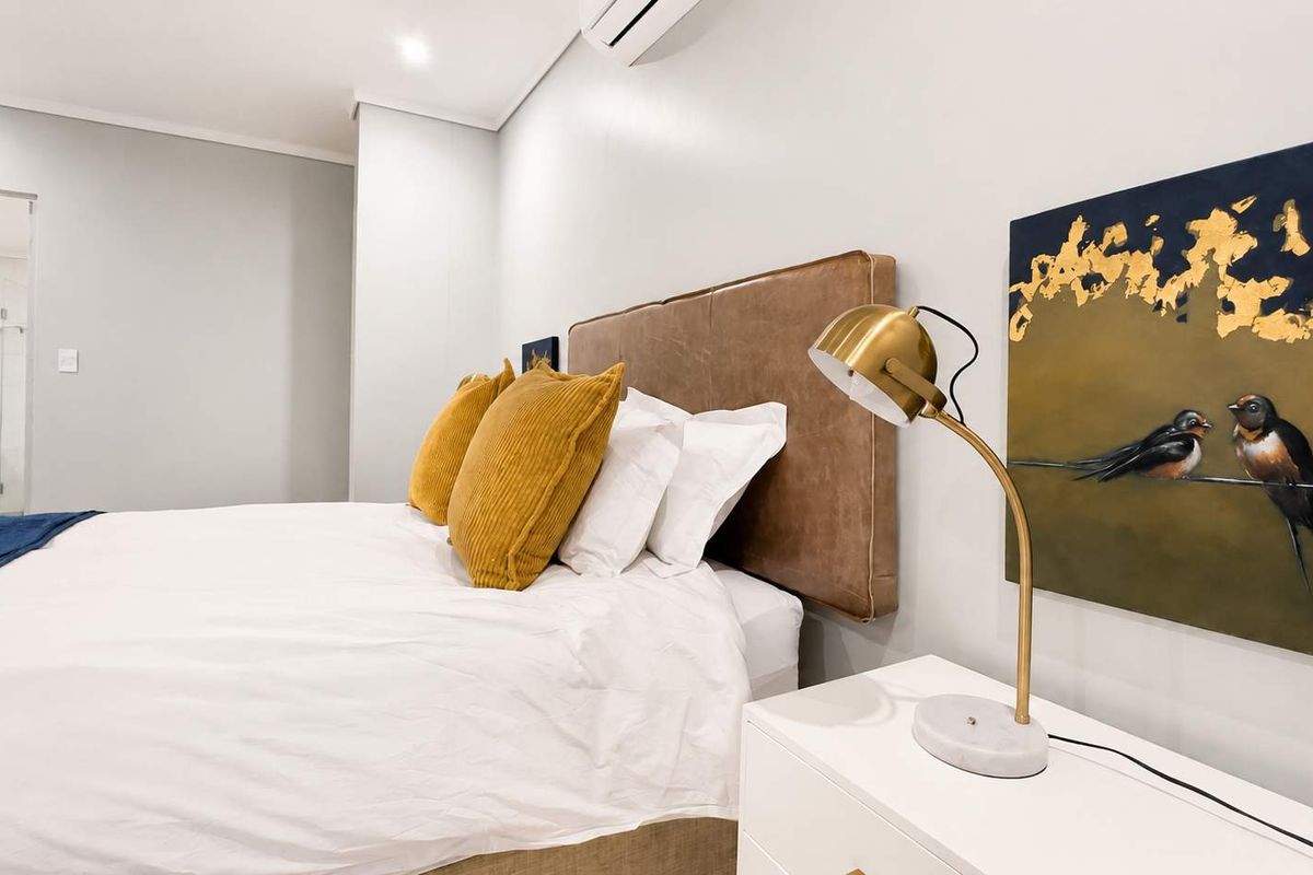 A well-maintained bedroom featuring neutral walls, recessed lighting, and an integrated air conditioning unit, with direct access to an en-suite bathroom.
