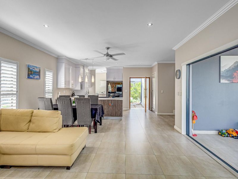 Spacious open-plan living and kitchen area featuring modern cabinetry, tiled floors, and large sliding doors providing seamless access to the outdoor patio.