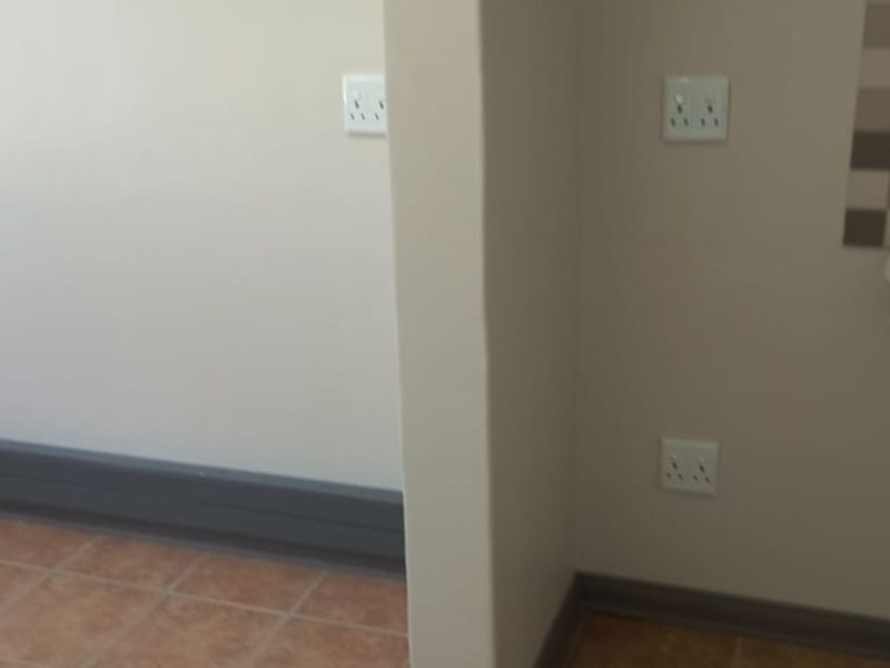A functional utility space featuring a wall-mounted basin with a tiled splashback and multiple electrical power outlets.