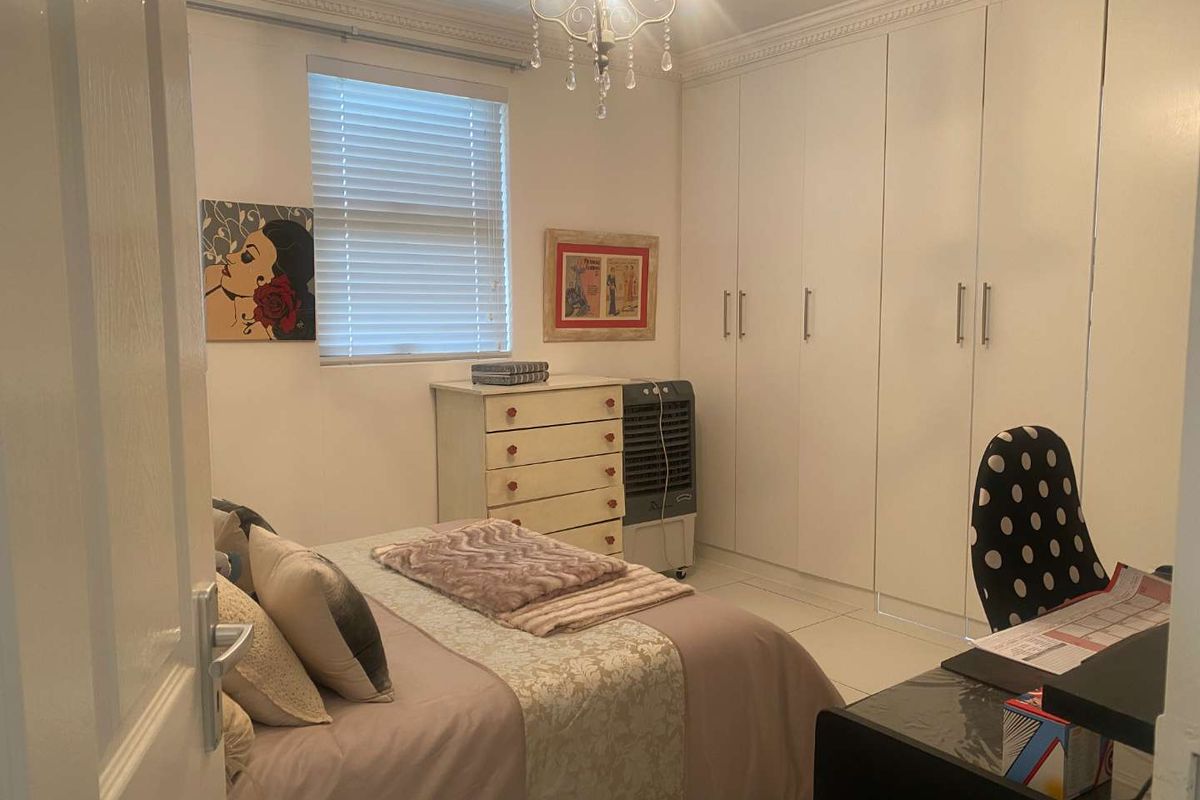 A bedroom featuring built-in floor-to-ceiling wardrobes, tiled flooring, and crown molding, providing ample storage and a clean, functional layout.