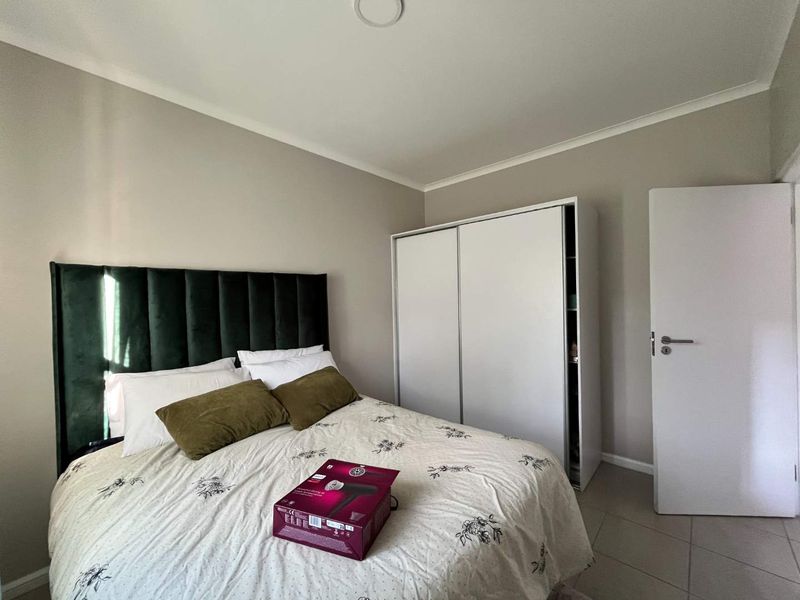 A well-maintained bedroom featuring neutral wall tones, tiled flooring, and a functional built-in wardrobe with sliding doors.
