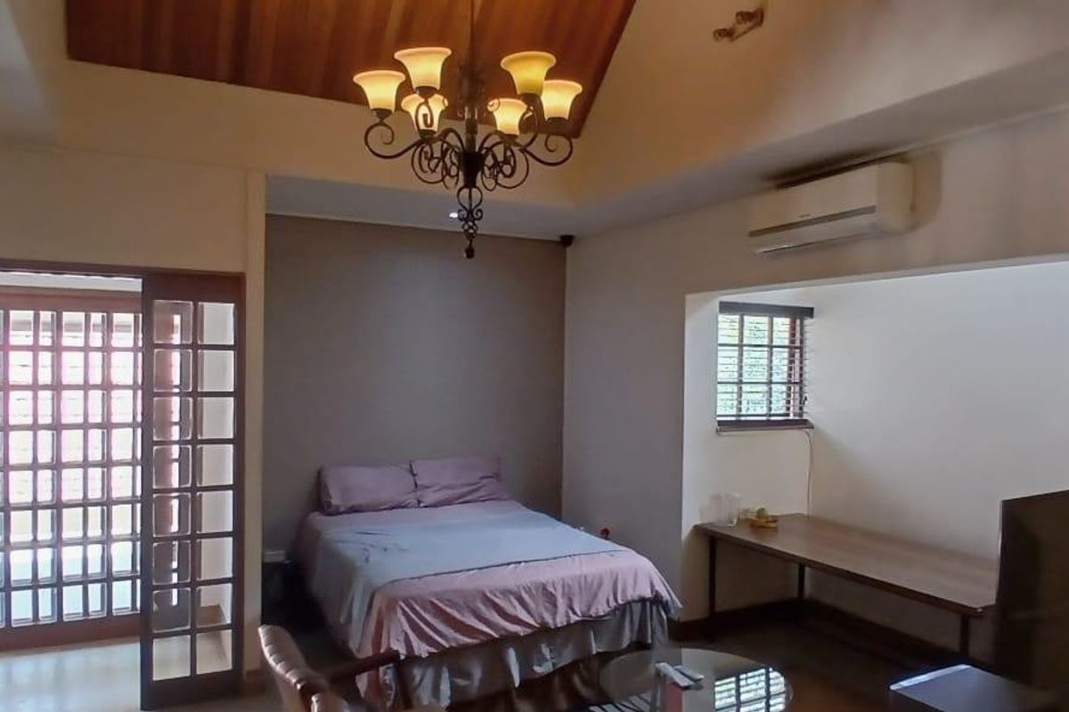 Spacious bedroom featuring a vaulted timber ceiling, wrought iron chandelier, split-system air conditioning, and a built-in desk area.