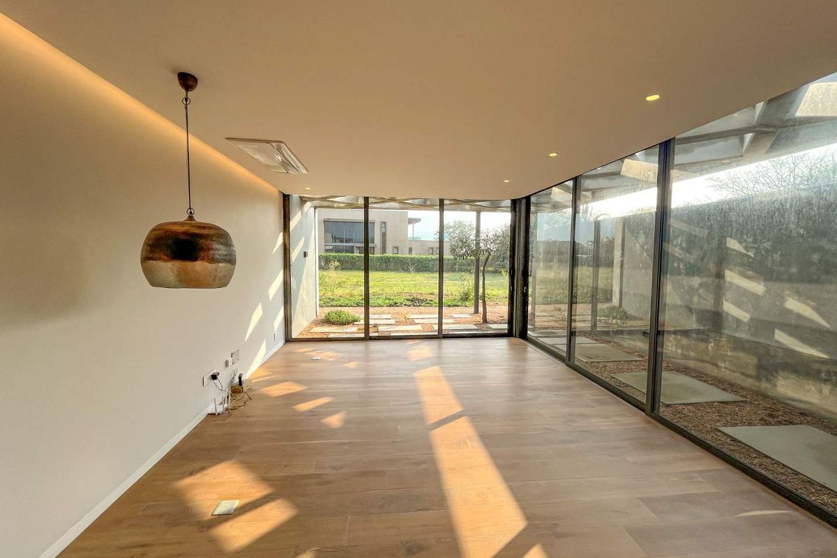 Bright, modern living space featuring floor-to-ceiling glass walls, recessed lighting, and high-quality timber flooring with direct access to the rear garden.