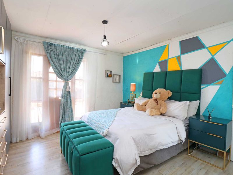 A well-lit bedroom featuring laminate flooring, a built-in wardrobe, and access to a balcony through classic french doors.
