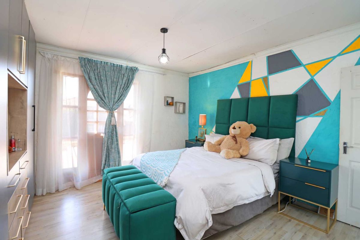 A well-lit bedroom featuring laminate flooring, a built-in wardrobe, and access to a balcony through classic french doors.