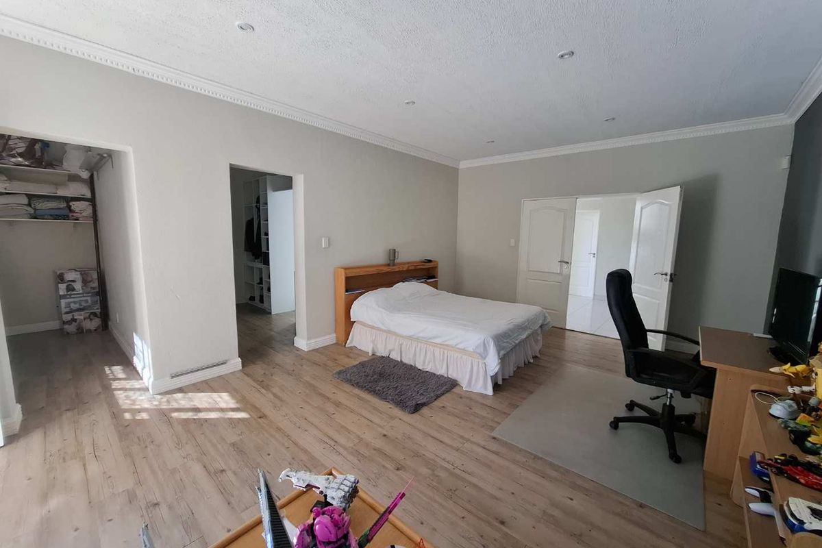 Spacious bedroom featuring light wood-look flooring, recessed ceiling lighting, crown molding, and an integrated walk-in closet area.