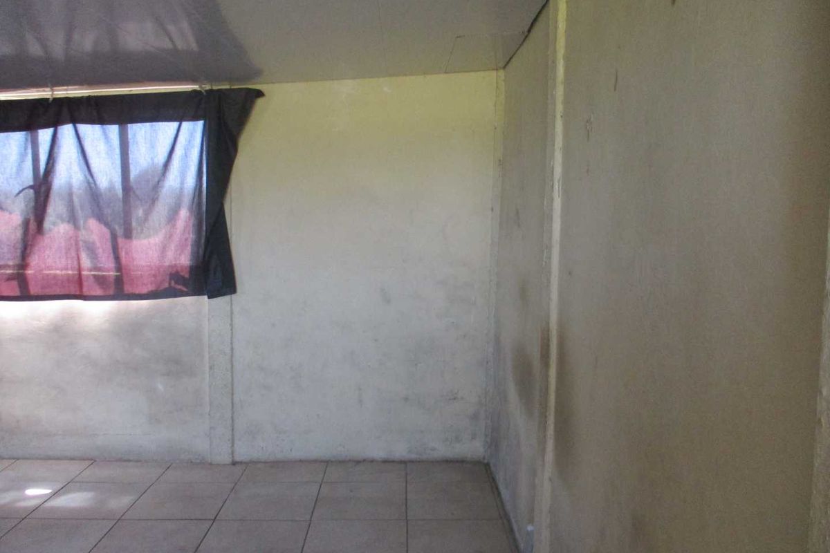 An empty bedroom featuring tiled flooring and walls requiring maintenance and cosmetic attention.