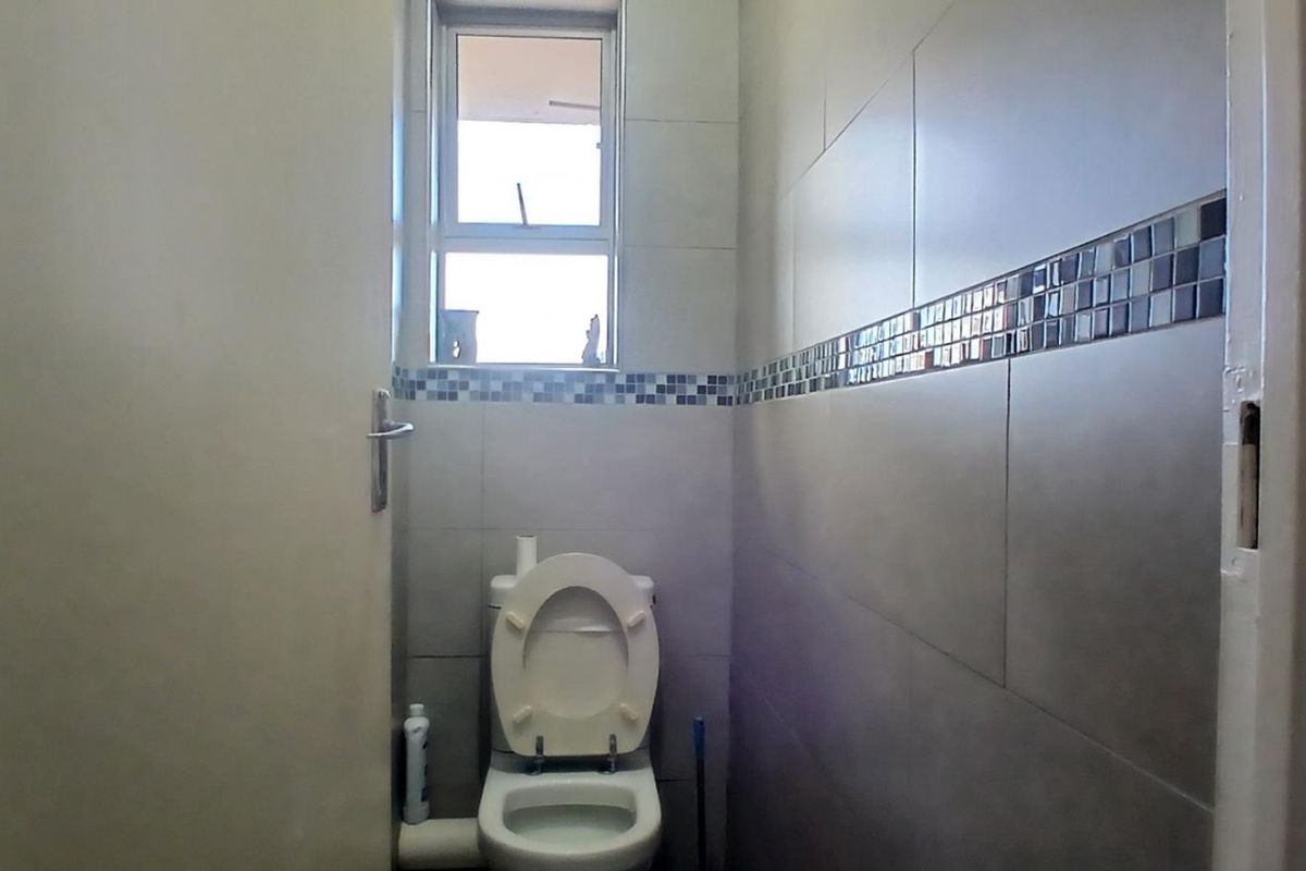 A compact bathroom featuring tiled walls with a decorative mosaic border and a window for natural light.