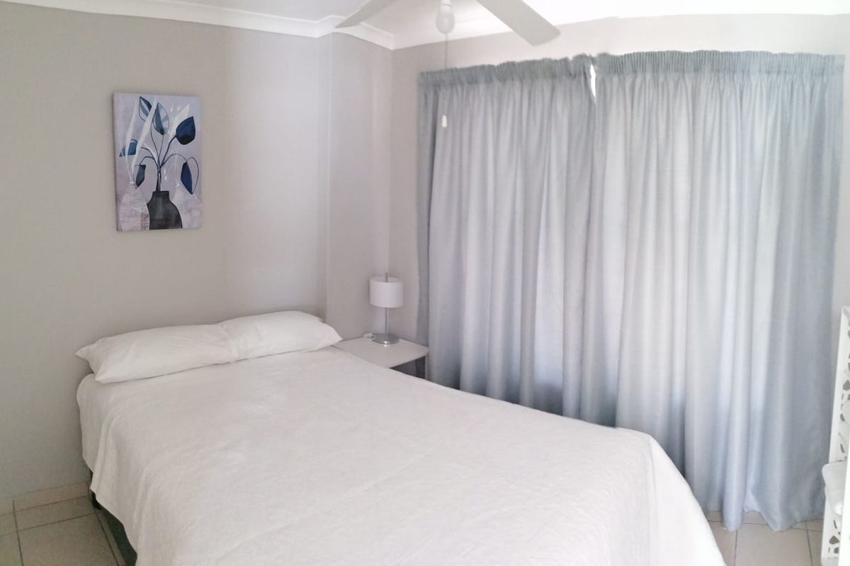 A functional bedroom featuring tiled flooring, a ceiling fan, and neutral wall finishes, providing a comfortable and well-maintained living space.