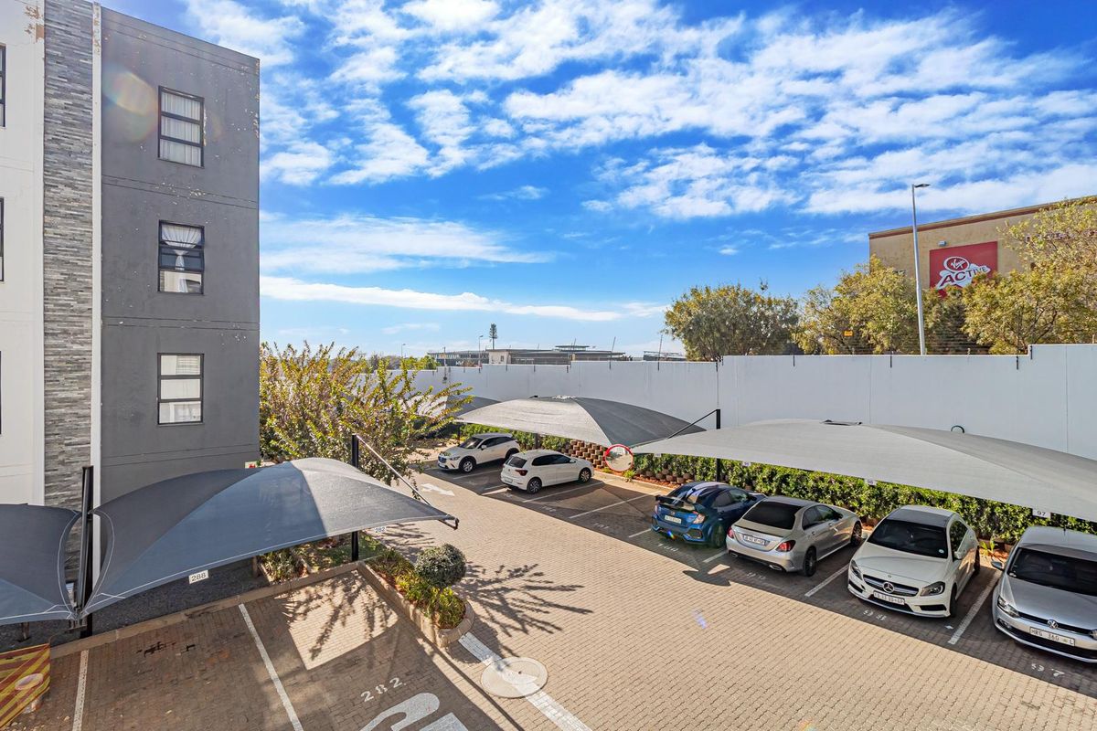 Exterior view of the apartment complex parking area featuring paved bays and shade cloth carports.