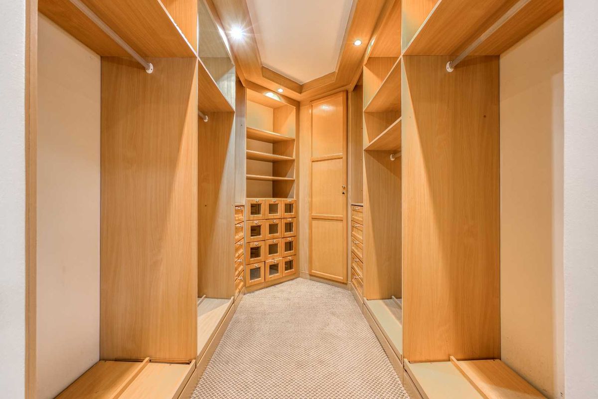 A well-maintained walk-in closet featuring extensive built-in wooden cabinetry, shelving, hanging rails, and recessed lighting.
