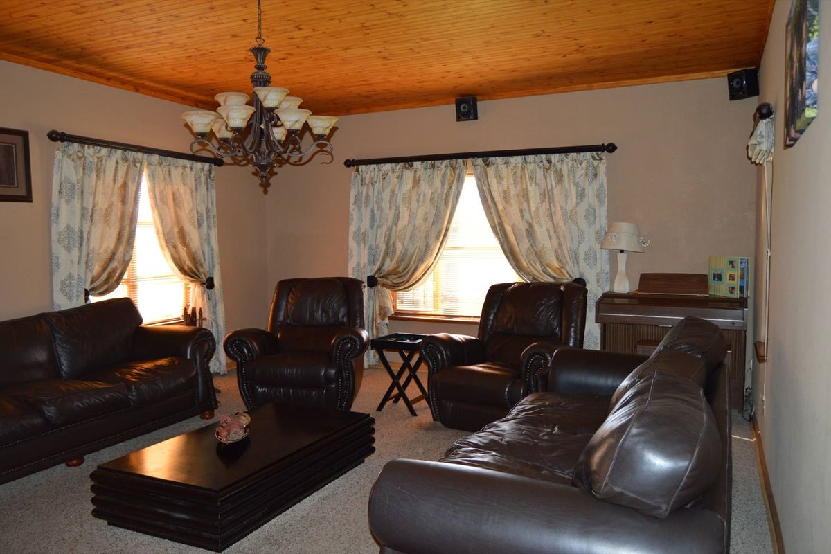 A traditional living room featuring a warm timber-clad ceiling, neutral wall tones, and carpeted flooring, providing a comfortable and classic living space.