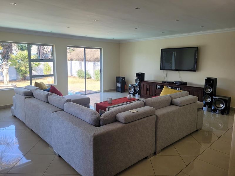 Spacious living room featuring large format floor tiles, recessed lighting, and sliding glass doors providing direct access to the outdoor pool area.