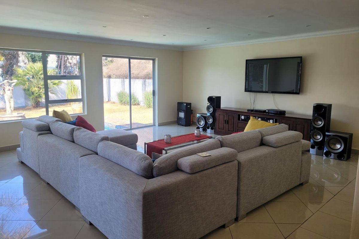 Spacious living room featuring large format floor tiles, recessed lighting, and sliding glass doors providing direct access to the outdoor pool area.