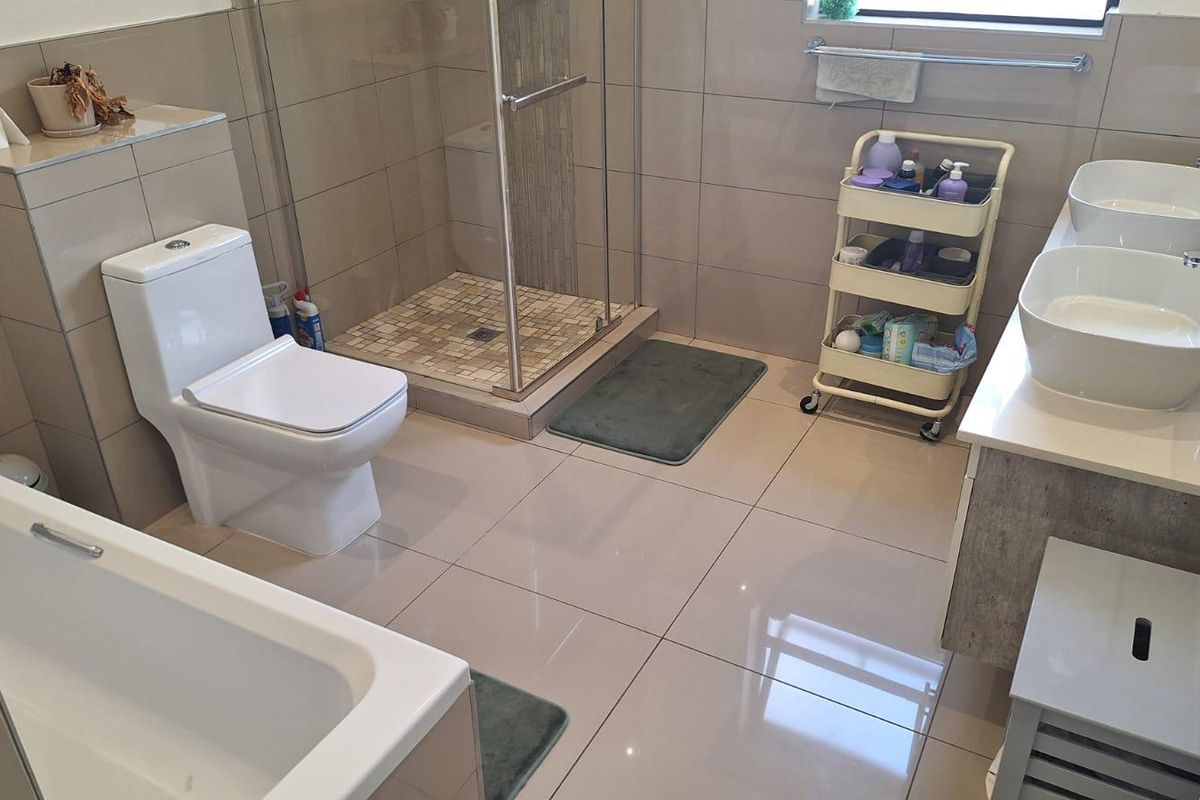 Modern bathroom featuring a double vanity with vessel sinks, a glass-enclosed shower, and a built-in bathtub with neutral floor-to-ceiling tiling.