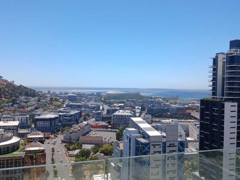 Elevated panoramic city and coastal view captured from a high-rise balcony with a modern glass balustrade.