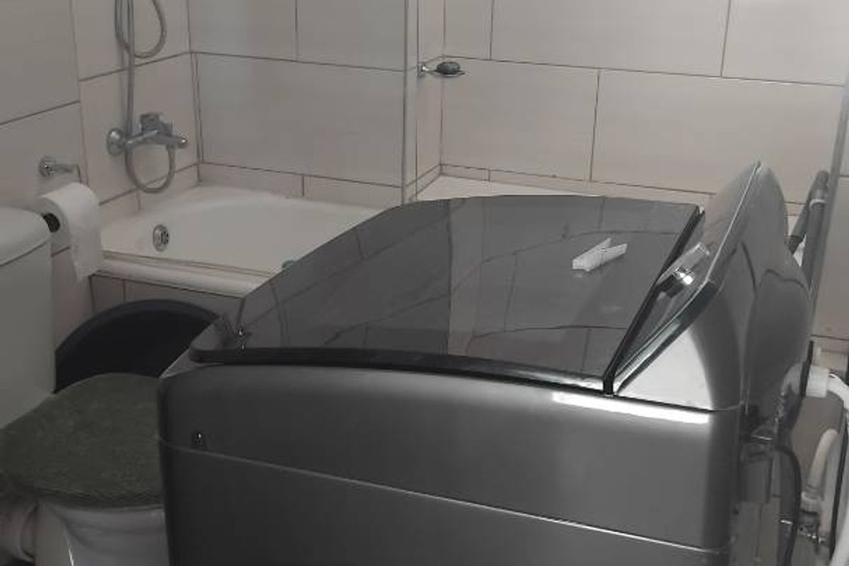 A functional bathroom featuring a combined shower and bathtub unit with wall-mounted shower fixtures and tiled wall finishes.