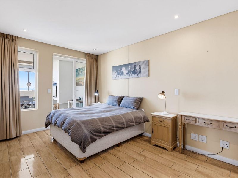 A well-lit bedroom featuring tiled flooring, recessed downlighting, and direct access to an adjoining balcony through a sliding glass door.