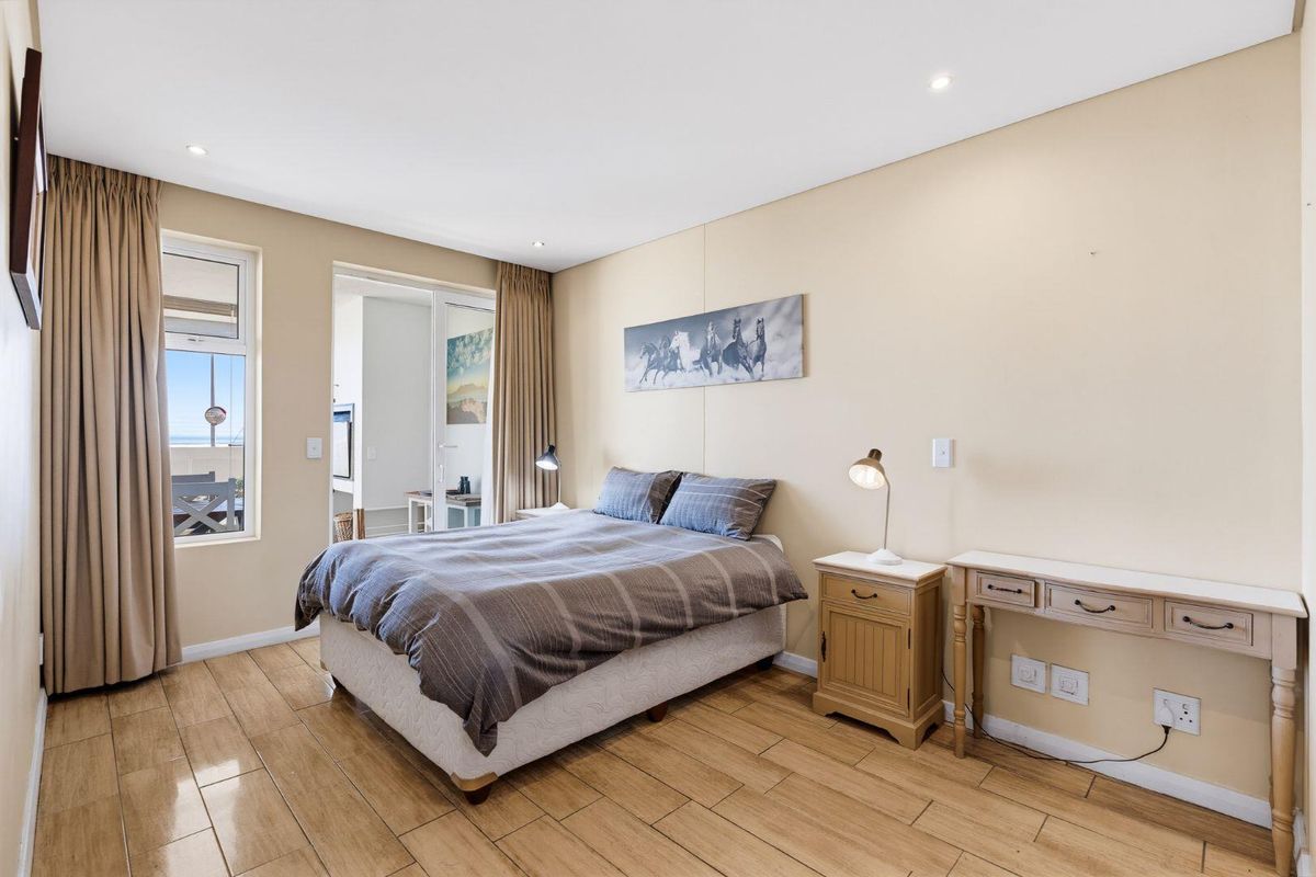 A well-lit bedroom featuring tiled flooring, recessed downlighting, and direct access to an adjoining balcony through a sliding glass door.