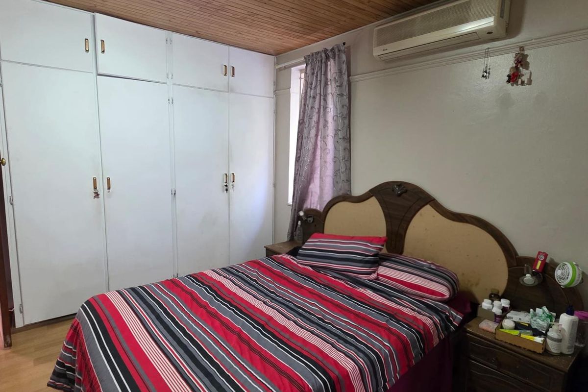 A bedroom featuring built-in floor-to-ceiling wardrobes, a timber-paneled ceiling, and a wall-mounted air conditioning unit.
