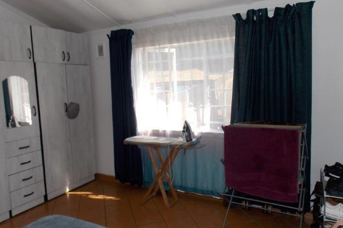 A functional bedroom featuring built-in cupboards and tiled flooring, providing ample storage space and a neutral foundation for personalization.