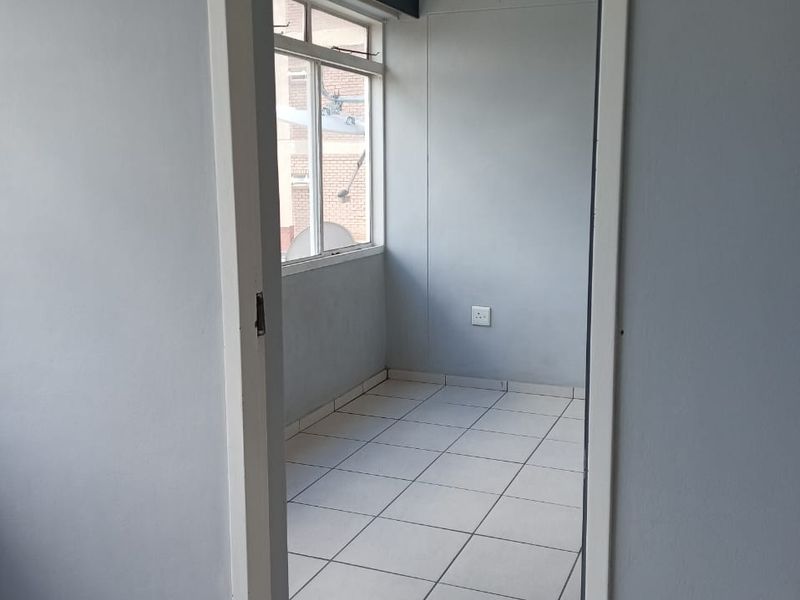An empty bedroom featuring tiled flooring and a window, providing a blank canvas for potential interior design and renovation.