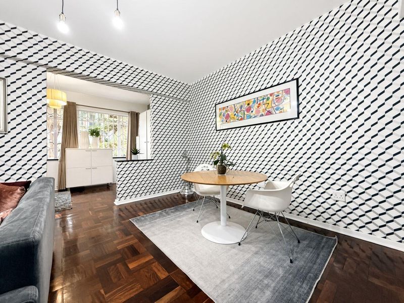 Open-plan living and dining area featuring classic parquet flooring and a convenient pass-through window connecting to the adjacent kitchen space.