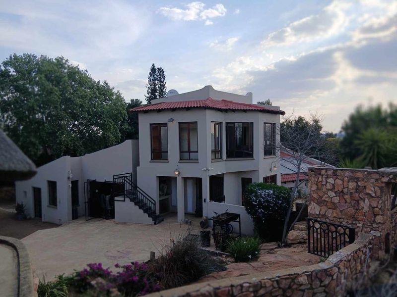 A multi-level residential property featuring terracotta roof tiles, stone cladding, and an external staircase leading to the upper level.