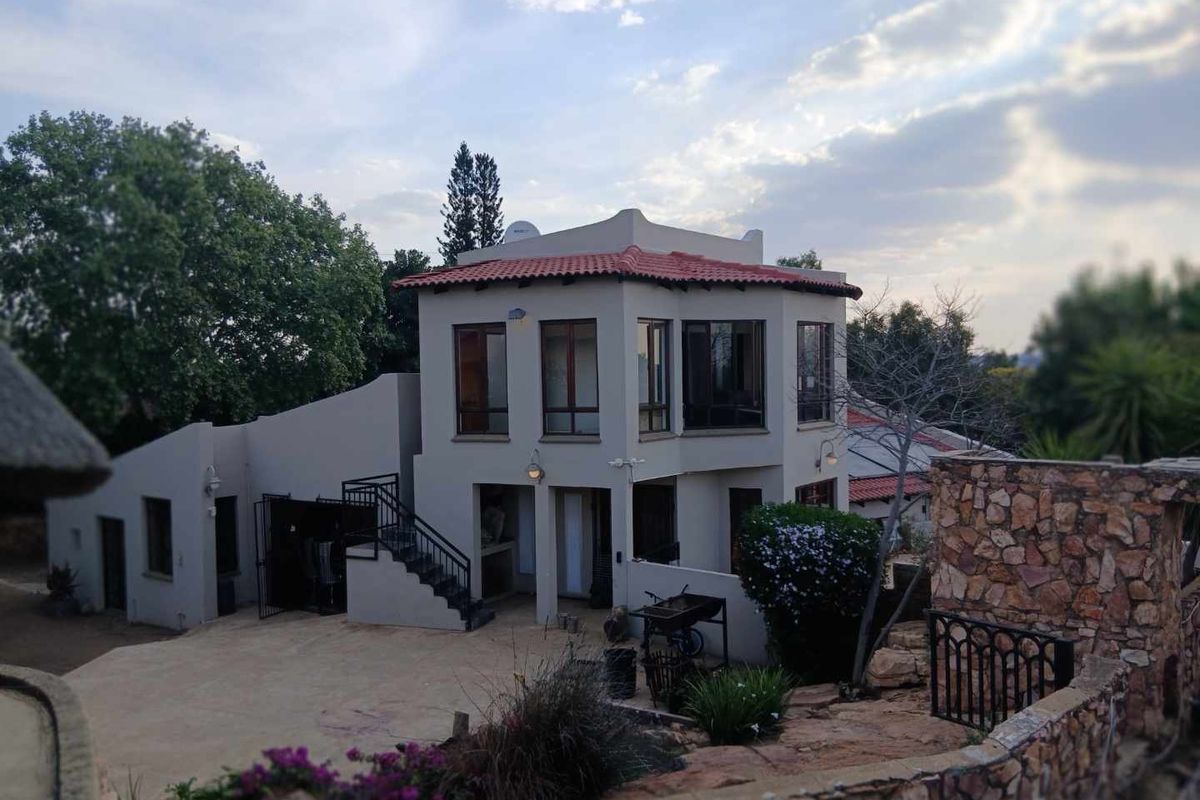 A multi-level residential property featuring terracotta roof tiles, stone cladding, and an external staircase leading to the upper level.