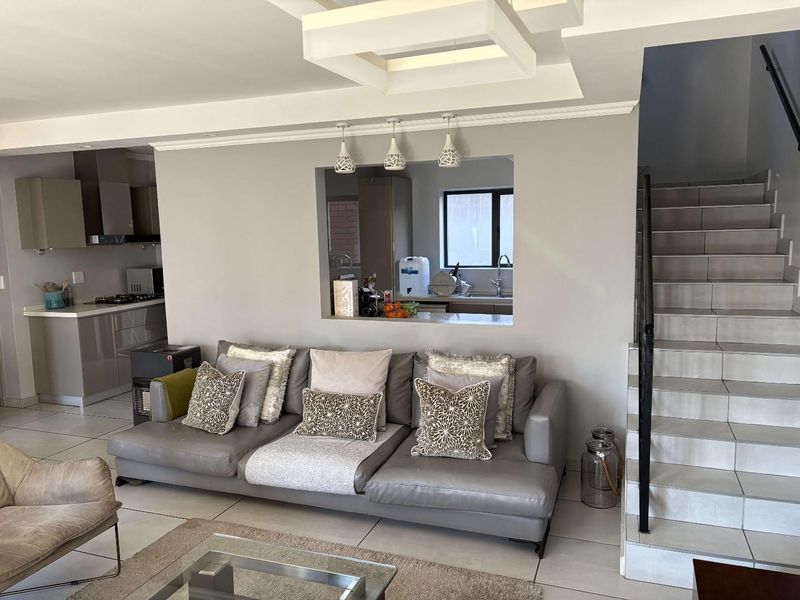 Open-plan living area featuring a modern kitchen with built-in cabinetry, tiled floors, and a staircase leading to the upper level.