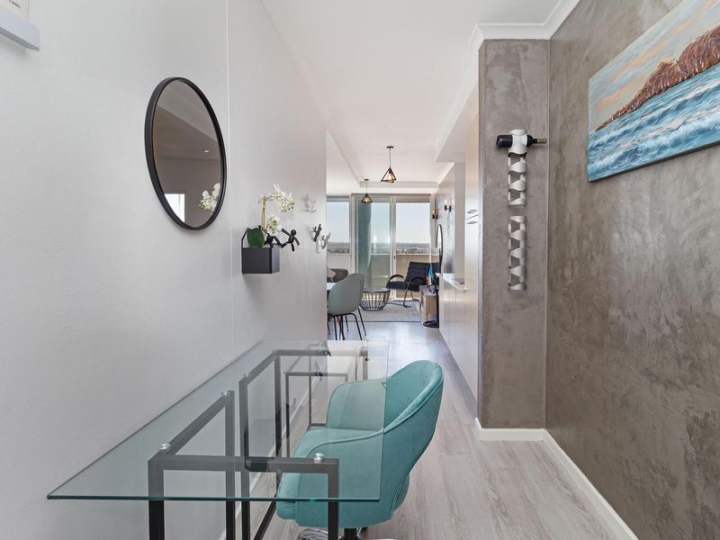 A modern, well-lit hallway featuring laminate flooring, a textured feature wall, and integrated cabinetry leading towards an open-plan living area.