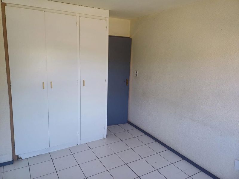 An empty bedroom featuring white built-in cupboards and tiled flooring, providing a blank canvas for personalization.