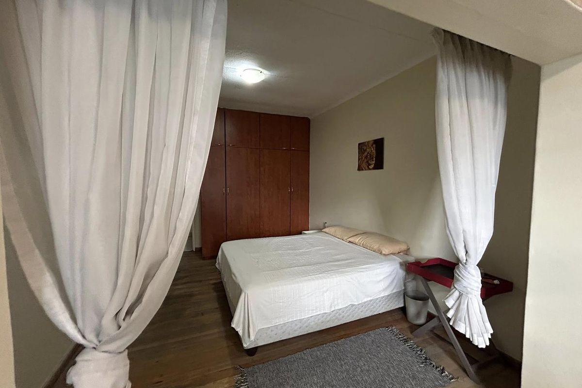 A bedroom featuring built-in wooden cupboards and wooden flooring, offering a functional and comfortable living space.