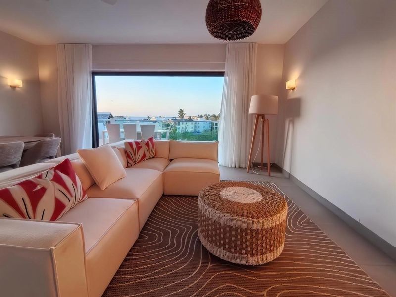 Modern living room featuring large sliding glass doors that open to a balcony with scenic views, complemented by neutral finishes and ambient lighting.