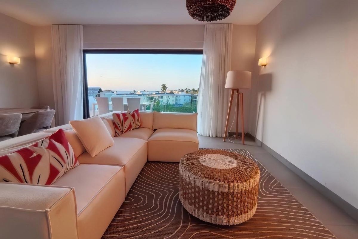 Modern living room featuring large sliding glass doors that open to a balcony with scenic views, complemented by neutral finishes and ambient lighting.
