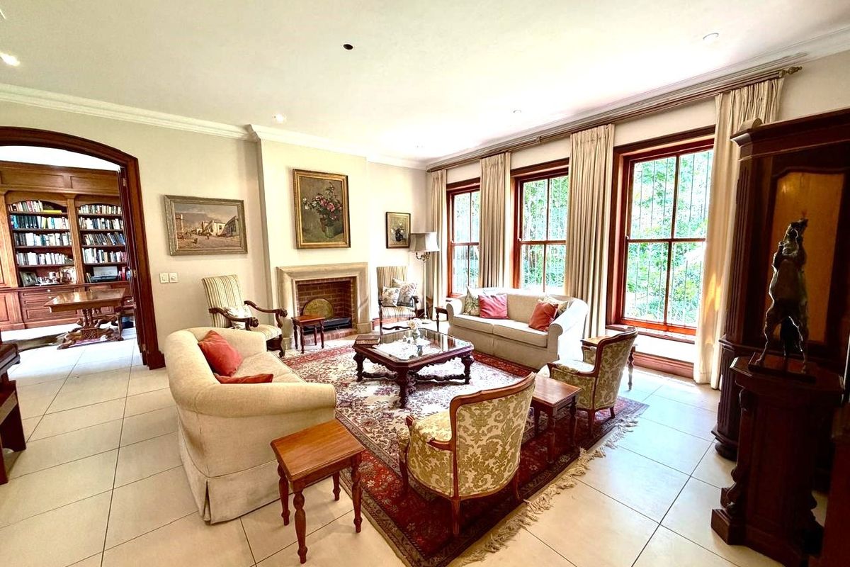 Spacious living room featuring a stone fireplace, large timber-framed windows, and neutral tiled flooring, offering a bright and elegant atmosphere.