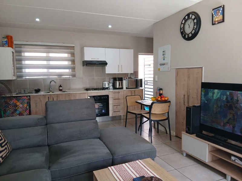 Open-plan living area featuring a modern kitchen with built-in cabinetry, gas hob, and tiled flooring, seamlessly integrated with the lounge space.