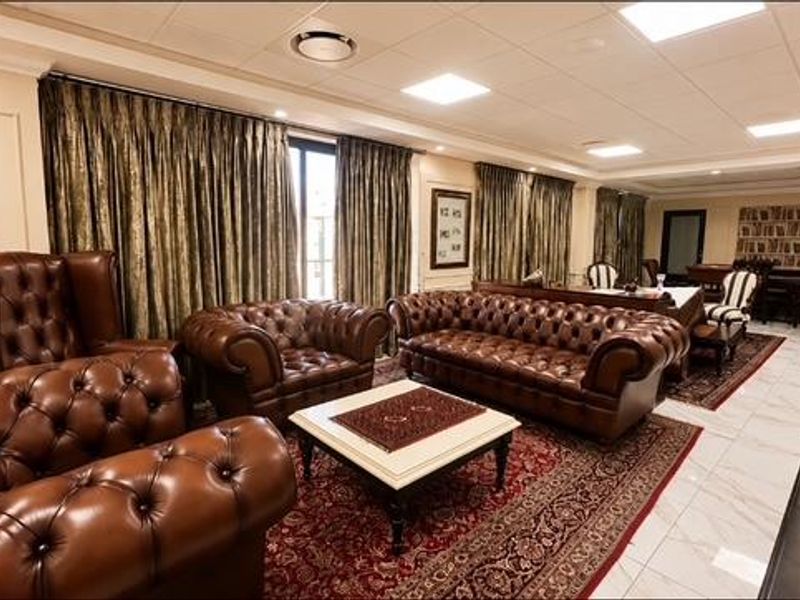 Spacious living area featuring polished tile flooring, recessed ceiling lighting, and elegant wall paneling, creating a sophisticated and well-maintained interior environment.
