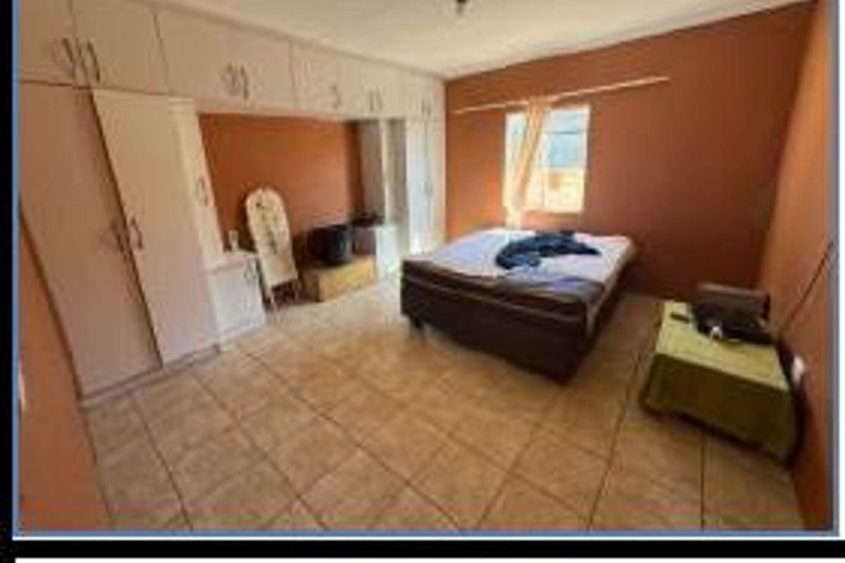 Spacious bedroom featuring built-in cabinetry, tiled flooring, and a window providing natural light.
