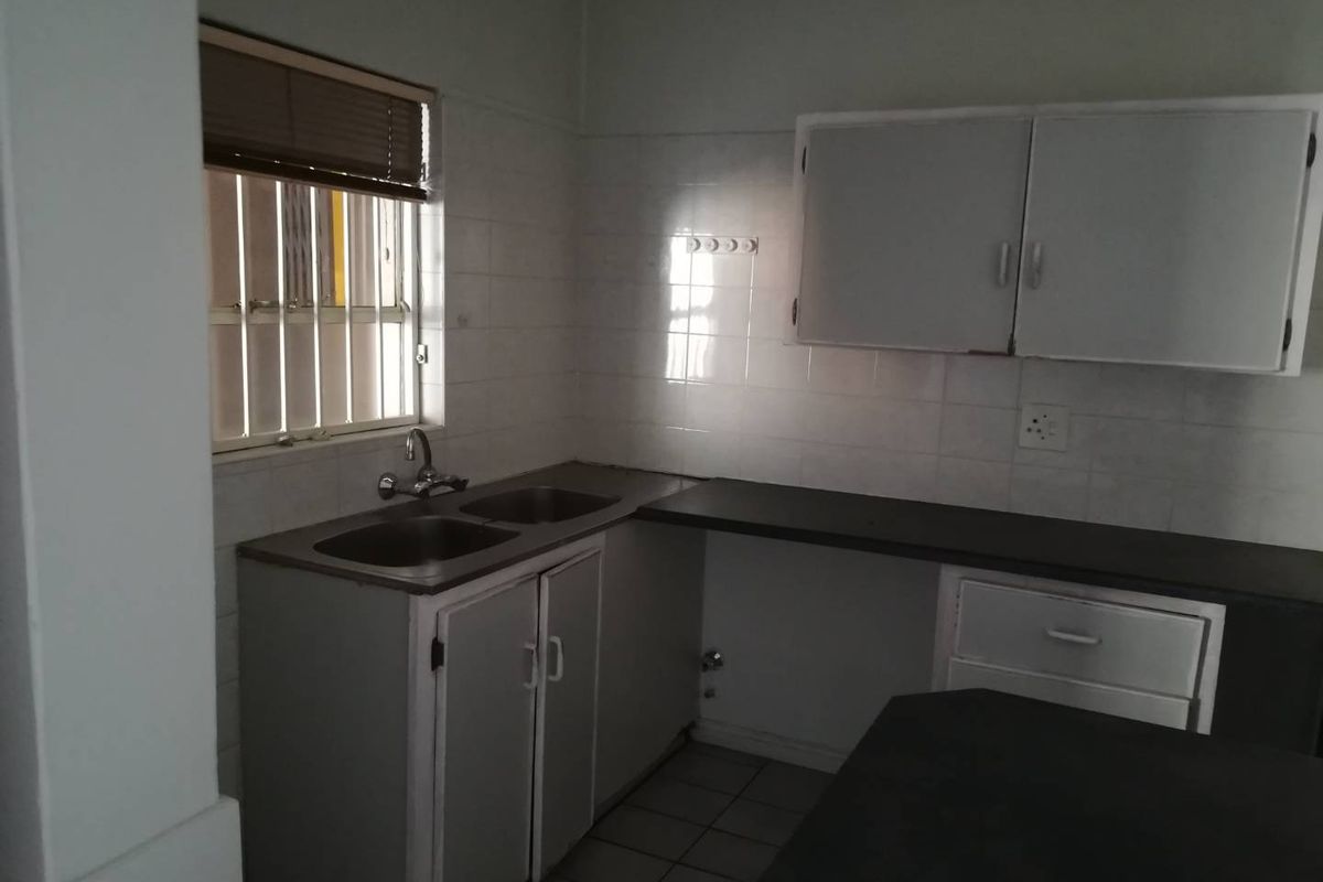 A functional kitchen space featuring built-in cabinetry, laminate countertops, and a double bowl sink, ready for modernization.