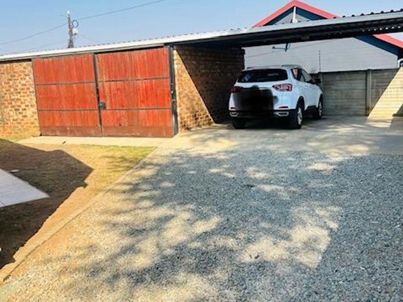 A functional carport and enclosed garage area with a gravel driveway, providing secure off-street parking.
