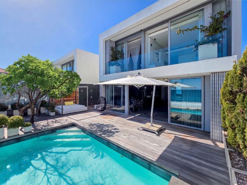 Modern townhouse exterior featuring a swimming pool, timber decking, and large sliding glass doors leading to the interior living spaces.
