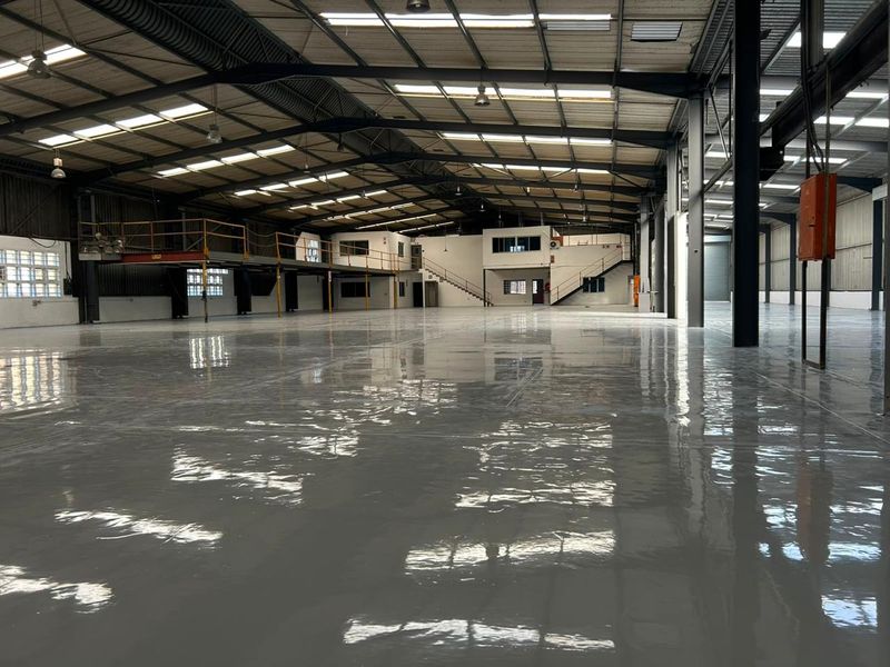 Spacious industrial warehouse featuring a high-gloss epoxy floor, steel portal frame construction, mezzanine level, and ample natural light through integrated skylights.