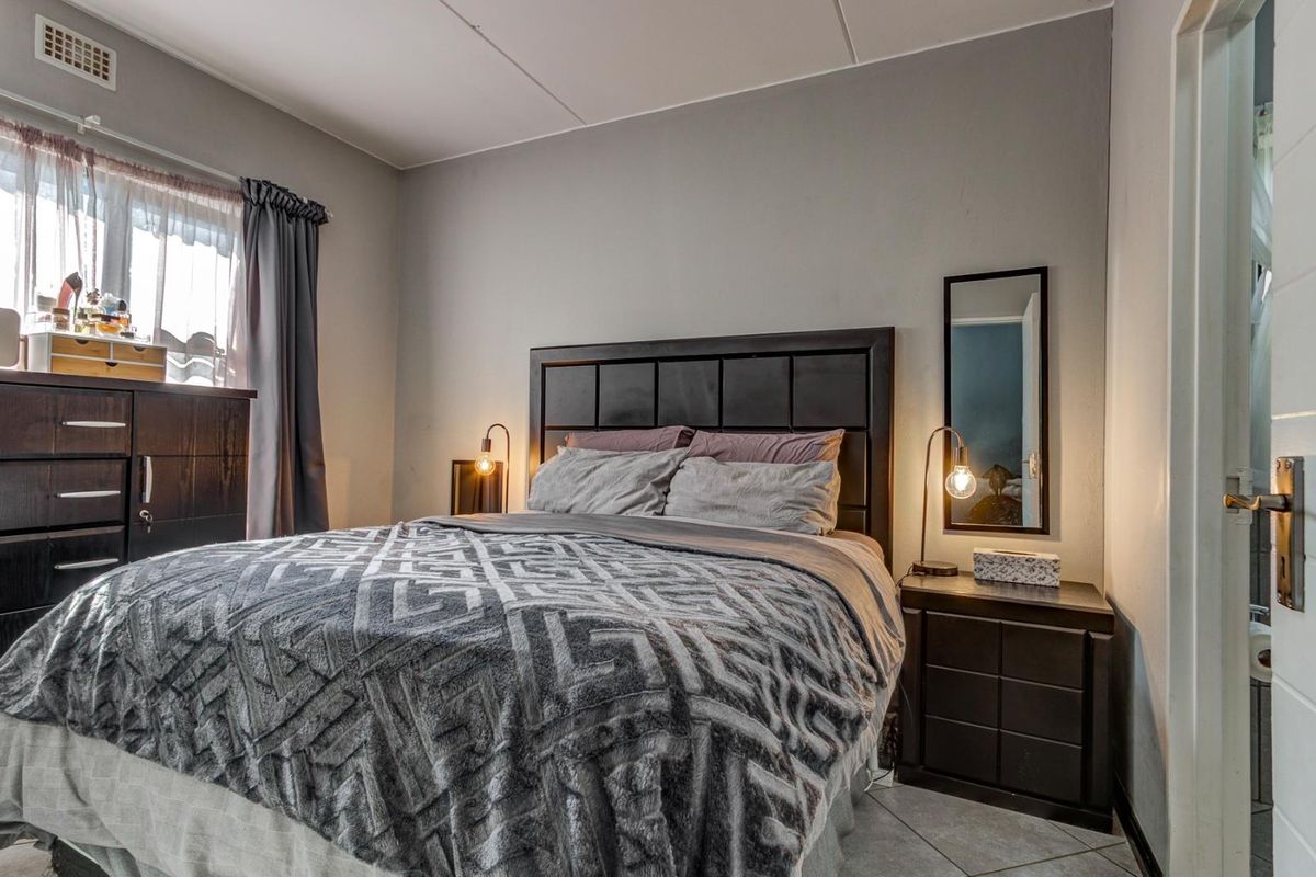 A bedroom featuring tiled flooring, a window with curtain tracks, and a neutral wall finish.